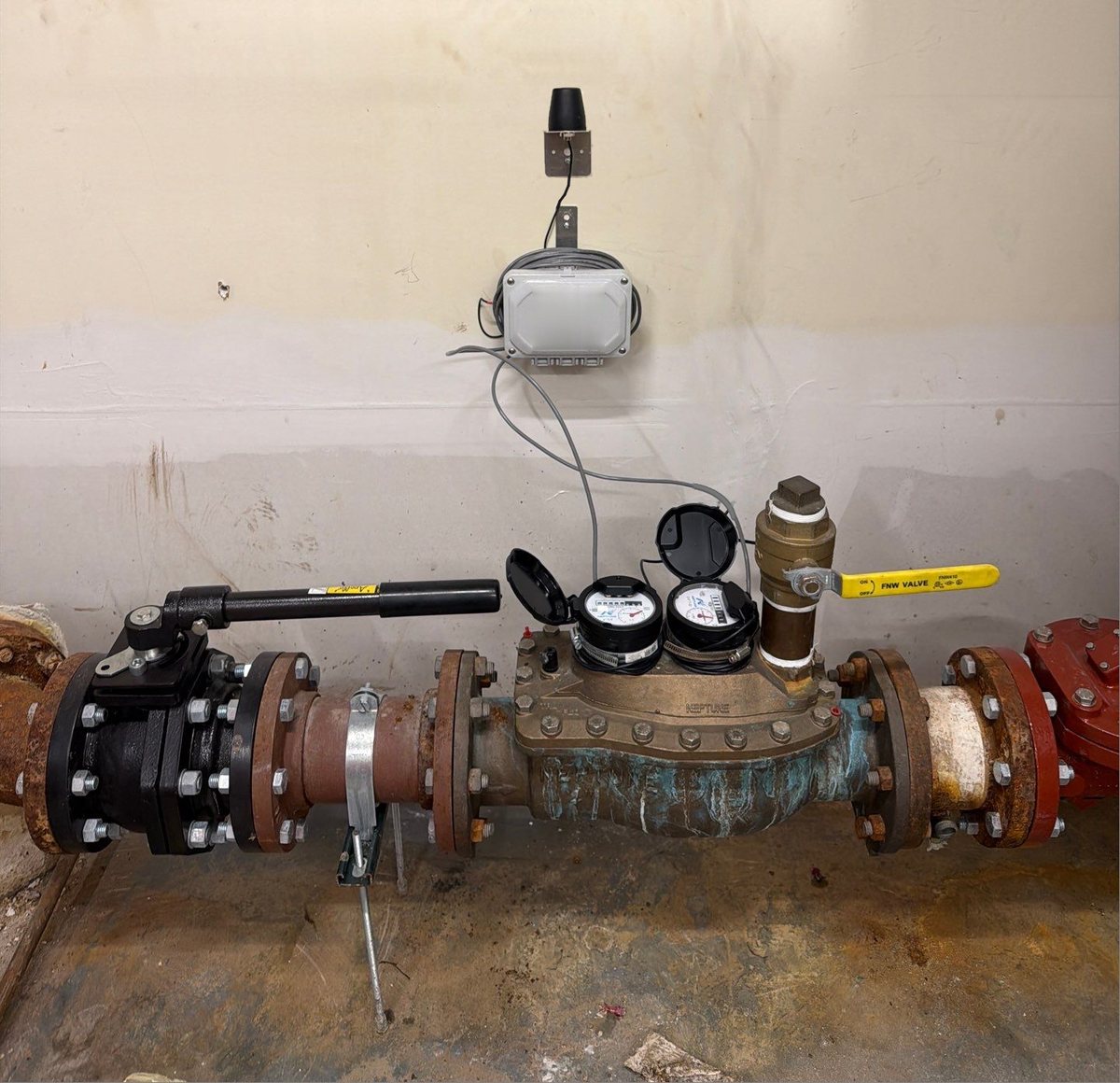 ProdigyLink real-time water monitor mounted on the wall above a building water meter